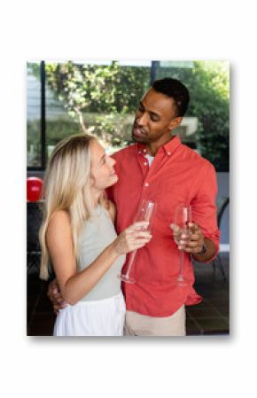 Couple celebrating at home, holding champagne glasses and smiling at each other