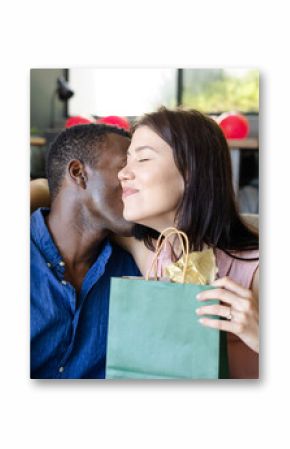 Couple embracing on sofa, exchanging gifts, celebrating special occasion at home