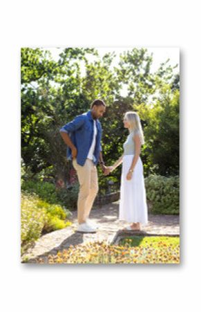 Couple holding hands in sunny garden, enjoying romantic moment together