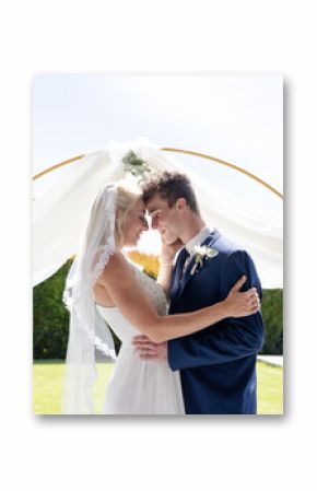 Bride and groom embracing under floral arch, sharing joyful moment outdoors