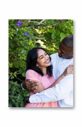 Couple embracing joyfully in garden, celebrating love amidst vibrant greenery