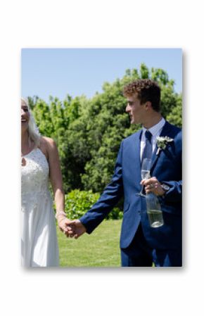 Bride and groom holding hands, smiling and celebrating outdoors with bubbles