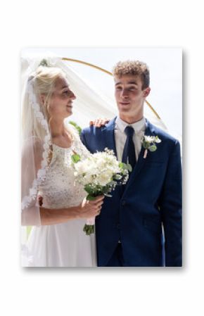 Bride and groom smiling joyfully outdoors, holding bouquet in sunny garden