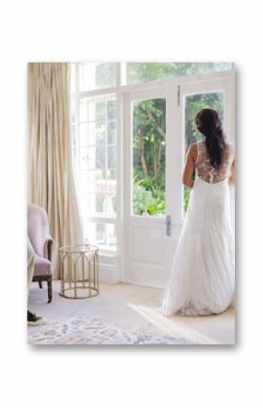 Photographer capturing bride in elegant gown standing by large window