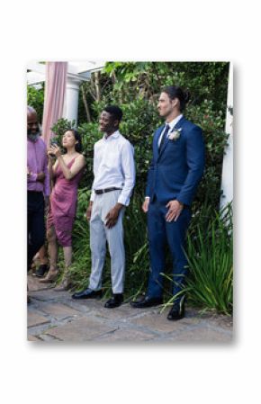 Bride in white dress walking towards groom in blue suit, guests smiling warmly