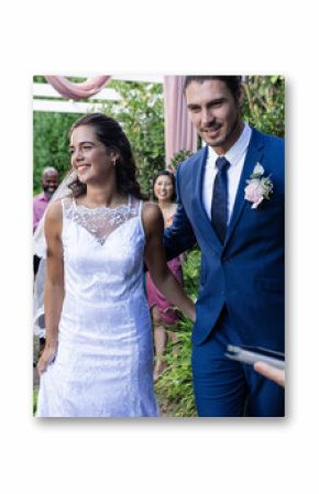 Bride and groom walking joyfully down garden aisle, guests applauding happily