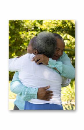 Senior couple embracing warmly in lush garden, enjoying sunny day together