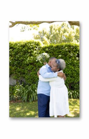 Senior couple embracing under tree in garden, enjoying peaceful moment together