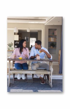 Couple enjoying breakfast together on patio, sharing conversation and drinks