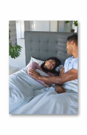 Couple relaxing in bed, sharing tender moment in cozy bedroom
