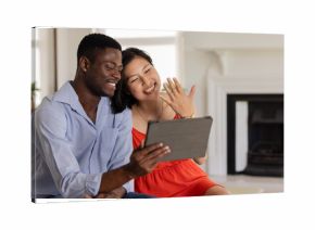 Happy couple video chatting, showing engagement ring, sitting together at home