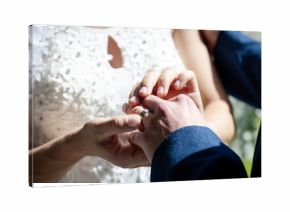 Bride placing ring on groom's finger during wedding ceremony, hands close-up