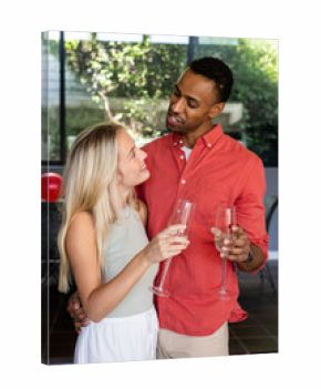 Couple celebrating at home, holding champagne glasses and smiling at each other