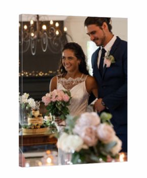 Bride and groom smiling, holding bouquet, celebrating wedding reception indoors
