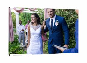 Bride and groom walking joyfully down garden aisle, guests applauding happily