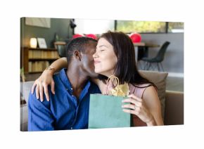 Couple embracing on sofa, exchanging gifts, celebrating special occasion at home