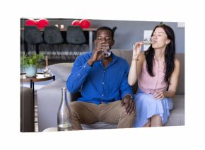 Couple enjoying drinks together on sofa, celebrating at home with champagne