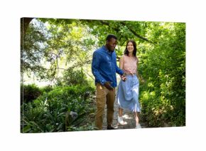 Couple walking hand in hand through lush garden, enjoying sunny day together