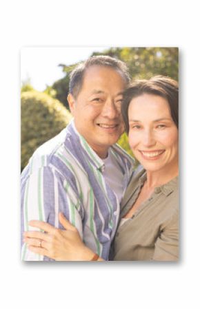 Embracing and smiling, couple enjoying time together outdoors in garden