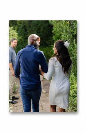 Couple walking hand in hand through garden, smiling and enjoying small casual wedding day
