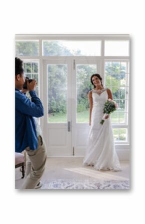 Bride in elegant white gown posing with bouquet while photographer captures moment