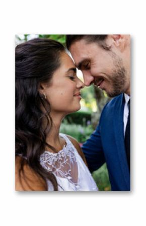 Bride and groom sharing intimate moment outdoors, smiling and embracing gently