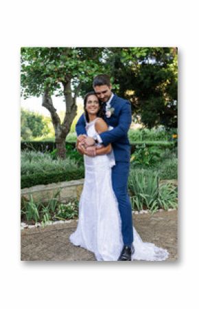 Bride and groom embracing in garden, smiling joyfully on wedding day