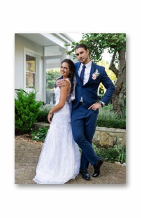 Bride and groom posing happily outdoors in elegant wedding attire