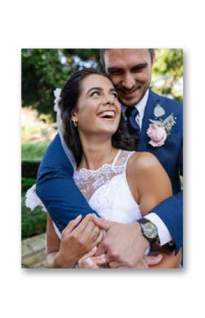 Bride and groom embracing outdoors, smiling joyfully on wedding day