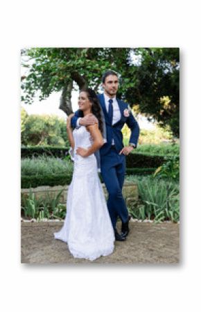 Bride and groom posing confidently in garden, celebrating their wedding day