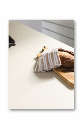 A loaf of bread is partially covered with a striped cloth on a kitchen counter with copy space