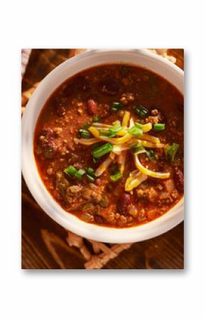 overhead photo of a bowl of chili with cheese and green onions