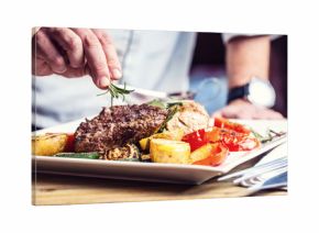 Chef in hotel or restaurant kitchen cooking only hands. Prepared beef steak with vegetable decoration.