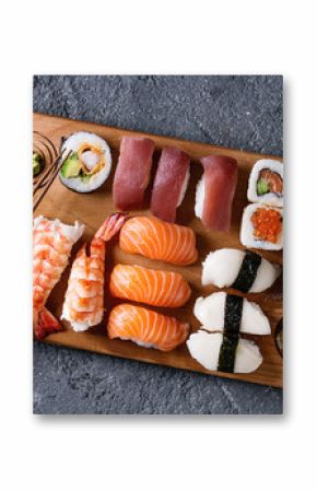 Sushi Set nigiri and sushi rolls on wooden serving board with soy sauce and chopsticks over black stone texture background. Top view with space. Japan menu