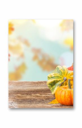 pile of orange raw pumpkins with fall leaves on wooden table over fall background