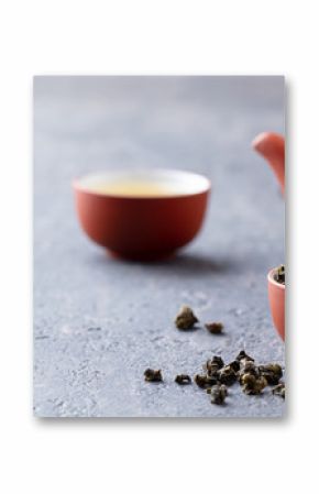 Green tea oolong in a clay tea cup bowl and tea pot. Stone background. Copy space.