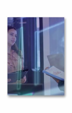 Four executives reviewing in glass office, with tablet clipboard laptop and data overlays