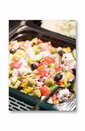 Displaying Greek salad glass tray on flat design buffet metal grid shelf, showing cucumbers, cheese