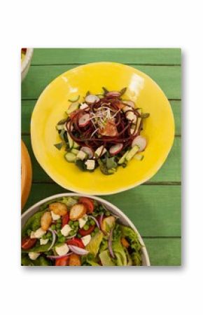Fresh food in bowls on green wooden table