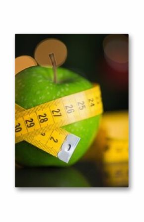 Green apple is sitting in flat design on glossy tabletop, with measuring tape and bokeh lights