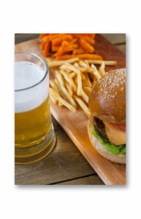 Beer mug, burger and fries on wooden table