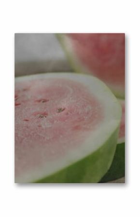 Displaying watermelon half slice showing red flesh with seeds and green rind on wooden board
