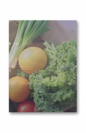 Burlap sack lined with green cloth resting on wooden dock by calm water, with fresh vegetables