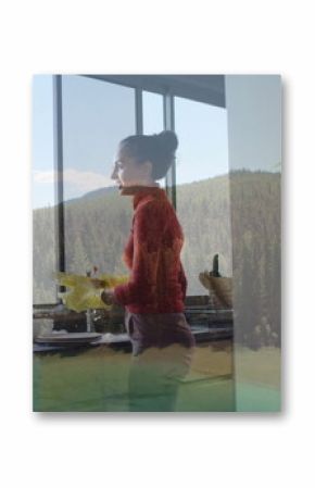 Mother and daughter chatting while holding mug and washing dishes wearing yellow gloves in kitchen