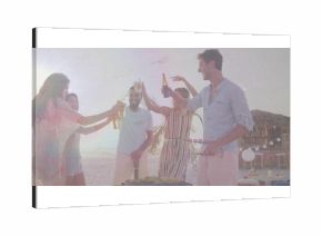 Friends raising beer bottles and toasting barbecue on sunset beach, with grill and string lights