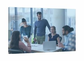 Team examining printed documents using laptop at conference table near windows with monitor, chairs