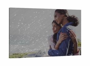 Leaning mother and daughter embracing balcony railing overlooking ocean waves and coastal houses