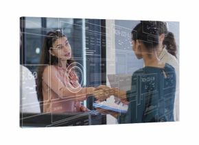 Business professionals shaking hands across glass table in office, featuring digital interface