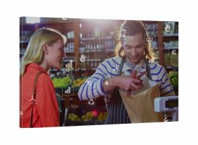 Packing clerk in apron placing red peppers into bag on scale in produce aisle, sustainability icons