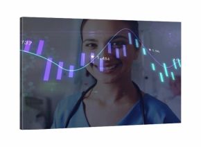 Smiling Indian nurse in scrubs with stethoscope standing in ward with beds, digital charts